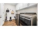 Well-lit laundry room featuring modern washer and dryer units, wooden floors, and storage cabinets at 4808 Jackson Club Loop, Tampa, FL 33624