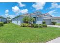 Charming single-story home with lush front lawn, beautiful landscaping, and a gray two-car garage at 5539 Silver Sun Dr, Apollo Beach, FL 33572
