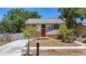 Charming home featuring a stone facade, bright red door, driveway, and tropical landscaping at 705 Cypress St, Tarpon Springs, FL 34689