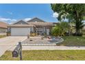 Well-manicured front yard featuring flowering bushes, rock garden, and a two-car garage at 7903 Lake Placid Ln, Trinity, FL 34655