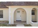 Close up of the home's arched front doorway with white trim and light fixture at 9922 86Th Way, Seminole, FL 33777