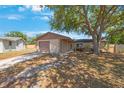 A single-story residential home has a tan exterior, a brown garage door, and a large tree in the front yard at 1159 19Th Sw Ave, Largo, FL 33778
