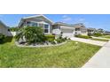Well-maintained gray home featuring lush landscaping and a two-car garage at 13357 Waterleaf Garden Cir, Riverview, FL 33579