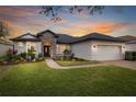 Charming home with a manicured lawn, stone accents, and a brick driveway at sunset at 14019 Nighthawk Ter, Lakewood Ranch, FL 34202
