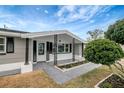 Charming porch with decorative support columns, modern lighting and landscape at 1516 Roundtree Rd, Holiday, FL 34690
