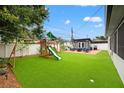 Backyard featuring artificial turf, a playset, and white privacy fencing at 1529 79Th N Ave, St Petersburg, FL 33702