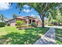 Beautiful single-story home with a well-maintained lawn, mature trees, and a welcoming entrance at 15724 Ibisridge Dr, Lithia, FL 33547