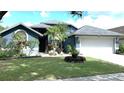 Charming blue home with manicured lawn, mature trees, and attached two-car garage at 16505 Lake Heather Dr, Tampa, FL 33618