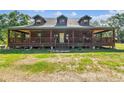 Rustic log cabin showcasing a generous covered porch, offering an ideal spot for relaxation and enjoying the natural surroundings at 19708 Bower Rd, Dade City, FL 33523