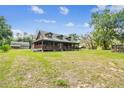 Sprawling log home featuring a welcoming front porch and scenic views of the lush, green landscape surrounding the property at 19708 Bower Rd, Dade City, FL 33523