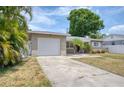 Exterior shot of home showing the garage and driveway, accented by palm trees and surrounding greenery at 211 80Th N Ave, St Petersburg, FL 33702