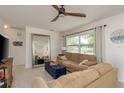 Bright living room with neutral walls, a large mirror, and comfortable tan sofas beneath a modern ceiling fan at 2153 Pocahontas Dr, Largo, FL 33774