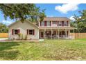 Charming two-story home with a welcoming front porch and red shutters at 2512 Rustic Oaks Dr, Lutz, FL 33559