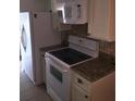 Bright kitchen featuring a white refrigerator, range, microwave, and stone countertops at 3115 Winchester Dr, Dunedin, FL 34698
