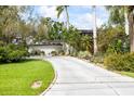 Landscaped yard leads to a mid-century modern home with white tiled walls and a flat roof design at 3130 Walnut Ne St, St Petersburg, FL 33704