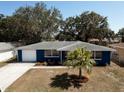 Aerial view of a charming blue home featuring a landscaped front yard and a garage on the left side at 3530 Umber Rd, Holiday, FL 34691