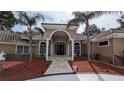 Elegant home with a columned entryway, arched windows, tile roof, and mature palm trees at 4872 Silverthorne Ct, Oldsmar, FL 34677