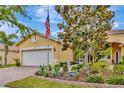 Charming single-story home with a well-manicured lawn, flag, and brick driveway at 4949 Marble Springs Cir, Wimauma, FL 33598