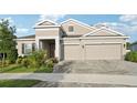 Beautiful home exterior with a three-car garage, manicured lawn, and lush landscaping, showcasing curb appeal at 5477 Wayfarer Ave, Apollo Beach, FL 33572
