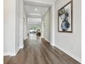 Spacious hallway with hardwood flooring, neutral paint, and a view into the open-concept living area at 5477 Wayfarer Ave, Apollo Beach, FL 33572