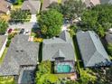 Aerial view of a property with a screened-in pool, surrounded by mature trees and neighboring houses at 7649 Nottinghill Sky Dr, Apollo Beach, FL 33572