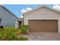 Close-up of the front exterior showcasing the home's neutral paint, brick-paved driveway and two car garage at 11830 Brighton Knoll Loop, Riverview, FL 33579