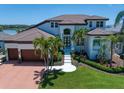 Beautiful home with a well-manicured lawn, elegant landscaping, and a grand entrance with an arched doorway at 14 Sunset Bay Dr, Belleair, FL 33756
