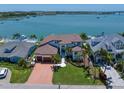 Beautiful waterfront home with lush landscaping, a brick driveway, and stunning water views at 14 Sunset Bay Dr, Belleair, FL 33756