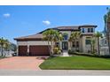 Elegant home featuring a spacious driveway, lush lawn, and meticulously landscaped front yard with palm trees at 14 Sunset Bay Dr, Belleair, FL 33756