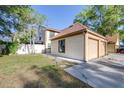 Exterior showcasing a two-car garage, a green lawn, and white fence surrounded by trees at 16107 Dawnview Dr, Tampa, FL 33624