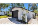 Exterior view of the garage, showing the black door, brick paved driveway, and new landscaping at 1710 Shore Acres Ne Blvd, St Petersburg, FL 33703