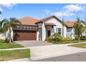 Charming one-story home featuring a terracotta roof, two-car garage, and well-manicured lawn at 17249 Star Banks St, Wimauma, FL 33598