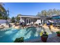 Backyard pool and patio area with chairs, potted plants, and a seating area under a blue umbrella at 1990 59Th N St, St Petersburg, FL 33710