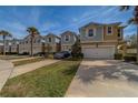 Townhome row showcasing two-car garages, well-kept lawns, and modern vehicles parked on concrete driveways at 2013 Sunset Wind Loop, Oldsmar, FL 34677