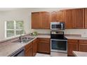 Kitchen features stainless steel appliances, wood cabinets, and a double sink beneath a window at 20221 Vintage Oaks Pl, Tampa, FL 33647