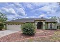 Charming home featuring a two-car garage, manicured lawn, arched entry and well-maintained landscaping at 5058 Westlake Blvd, Dade City, FL 33523