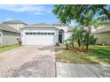 Well-maintained single-story home featuring a brick driveway, two-car garage, and manicured landscaping at 8407 Hunters Fork Loop, Ruskin, FL 33573
