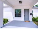 Welcoming covered front porch with gray flooring, a gray front door, and a window with blinds at 1051 44Th S St, St Petersburg, FL 33711