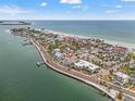 Stunning aerial view of the coastal town with white buildings next to a beach, ocean and a pier on a sunny day at 1104 Pass A Grille Way, St Pete Beach, FL 33706