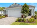 Charming home featuring a two-car garage, lush landscaping, and a brick-paved driveway at 11359 Boundless Ter, Venice, FL 34293