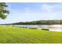 Expansive backyard with a serene lake view, lush green lawn, and benches to enjoy the natural surroundings at 1768 Lago Vista Blvd, Palm Harbor, FL 34685