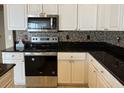 Updated kitchen features sleek black countertops, stainless steel appliances, and white cabinetry at 2213 Towering Oaks Cir, Seffner, FL 33584