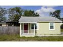 Charming single-story home featuring a red front door, light green siding, and a cozy front porch at 3412 N 54Th St, Tampa, FL 33619