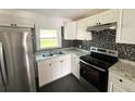 Modern kitchen with stainless steel appliances, white cabinets, granite counters, and tiled backsplash at 3412 N 54Th St, Tampa, FL 33619