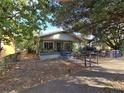 Quaint bungalow with inviting front porch, framed by mature trees, enclosed with a metal chain-link fence at 3503 N 11Th St, Tampa, FL 33605