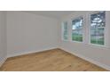 Bright bedroom showcasing hardwood floors, white walls, baseboards and three windows offering ample natural light at 3614 W Platt St, Tampa, FL 33609