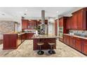 Gourmet kitchen featuring custom cabinetry, granite countertops, and a stainless steel island hood at 4690 Wrentham Pl, Palm Harbor, FL 34685