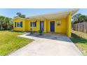 View of the yellow house featuring a covered parking area with blue doors and white trim at 6750 Hibiscus S Ave, South Pasadena, FL 33707