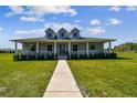 Charming single Gathering home featuring a wraparound porch, well-manicured lawn, and inviting curb appeal at 7627 Artifact Dr, Zephyrhills, FL 33541