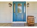 Close-up of a bright blue front door, decorative glass, stylish lanterns, and a welcome mat at 7627 Artifact Dr, Zephyrhills, FL 33541